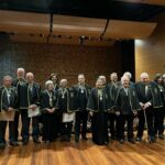 Novos acadêmicos estão em pé, no palco.