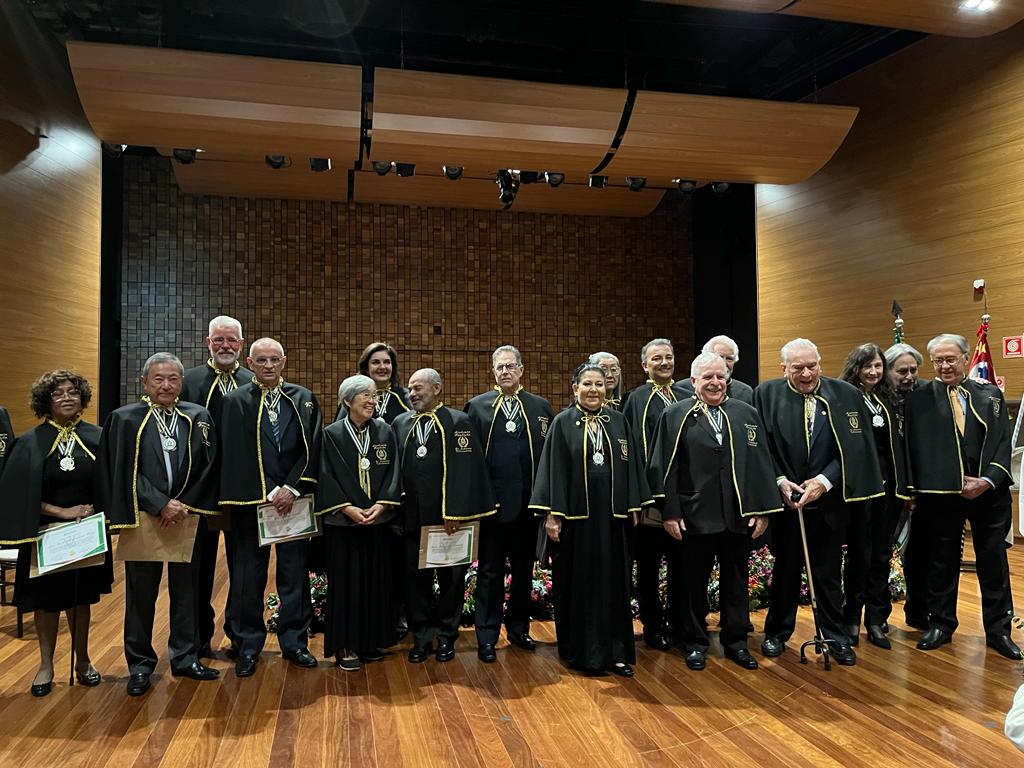 Novos acadêmicos estão em pé, no palco.