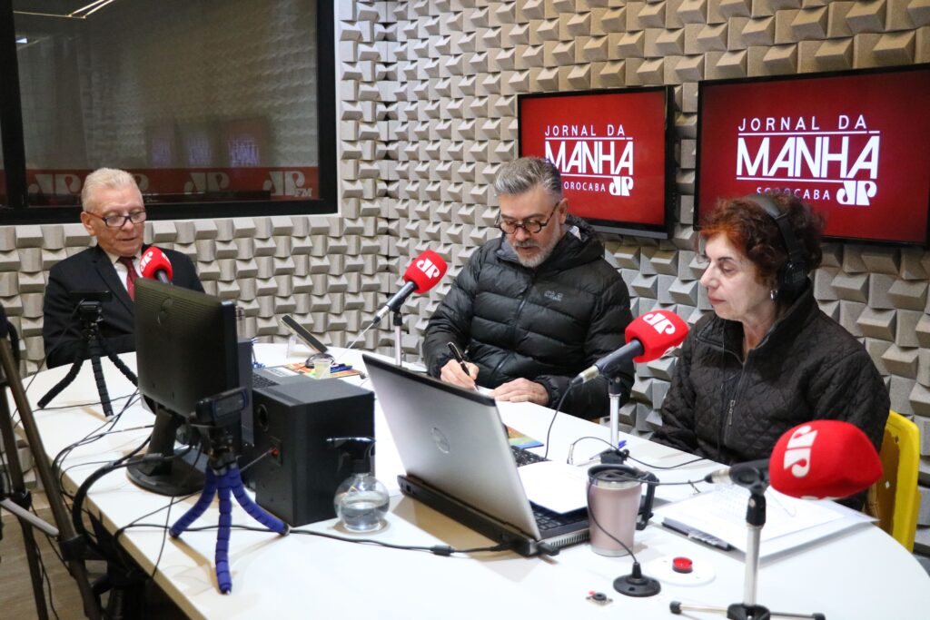 O presidente do CRMV-SP, Odemilson Donizete Mossero, está ao lado dos radialistas da Jovem Pan Sorocaba, em estúdio, sentado, gravando.