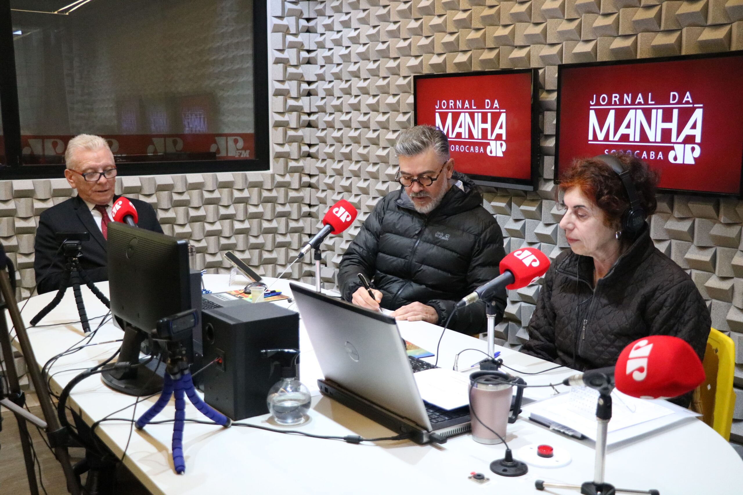 O presidente do CRMV-SP, Odemilson Donizete Mossero, está ao lado dos radialistas da Jovem Pan Sorocaba, em estúdio, sentado, gravando.