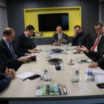 Na foto estão os membros do CRMV-SP e o presidente da APM. Eles estão sentados em uma mesa retangular, e conversam.