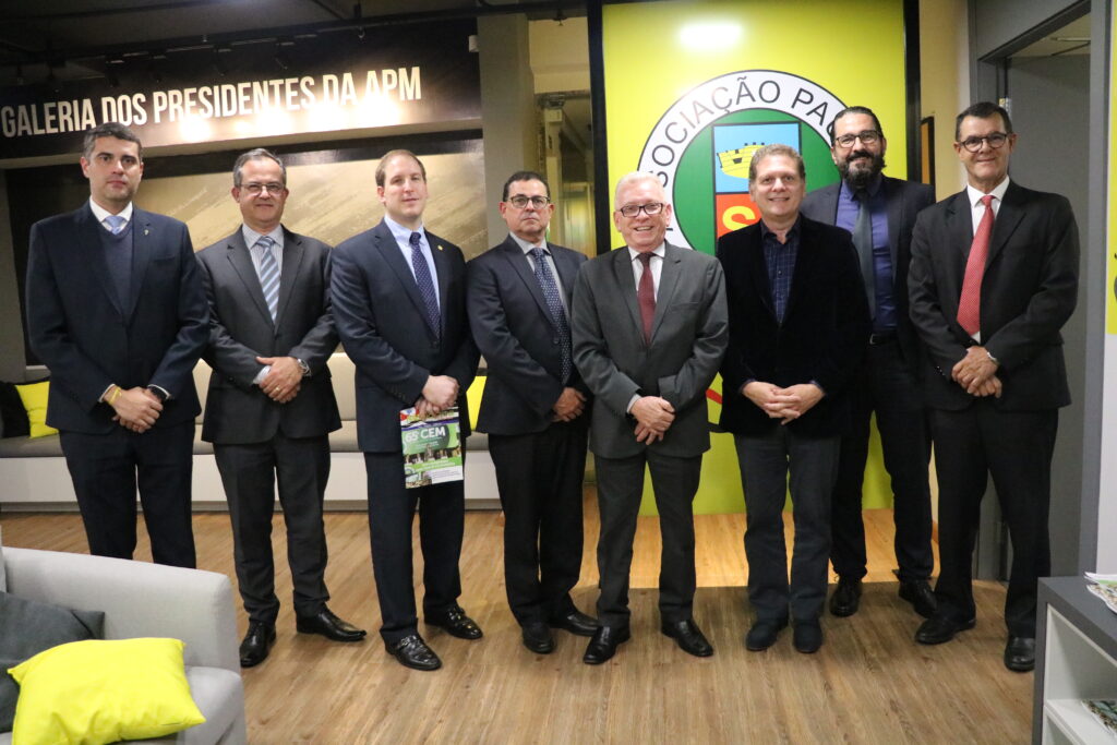 Os membros do CRMV-SP e o presidente da APM estão em pé, posando para a foto. Atrás está o logo da APM, com fundo verde.