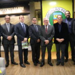 Os membros do CRMV-SP e o presidente da APM estão em pé, posando para a foto. Atrás está o logo da APM, com fundo verde.