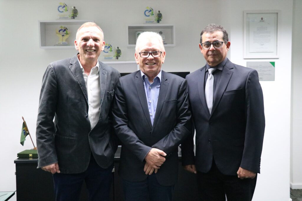 Na foto há três homens de meia idade, sorrindo para a foto, de pé e posados lado a lado. Eles vestem terno cinza com camisa, dois deles usam óculos e outro usa gravata de cor clara. Trata-se dos presidentes do Sindimvet e do CRMV-SP, e do secretário geral da autarquia.