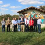 O médico-veterinário Aluísio Marins, diretor técnico da instituição, e o professor e empresário, Luiz Marins, estão na foto posando ao lado dos membros do CRMV-SP. O chão é um gramado bem verde e ao fundo há uma casa. O céu está bem azul e com muitas nuvens brancas.