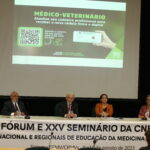 Na foto, está a mesa do evento com os membros principais, entre os quais o presidente do CFMV. Há uma faixa escrita Primeiro Fórum e Vigésimo Quinto Seminário das Comissões Nacional e Regionais de Educação da Medicina Veterinária.