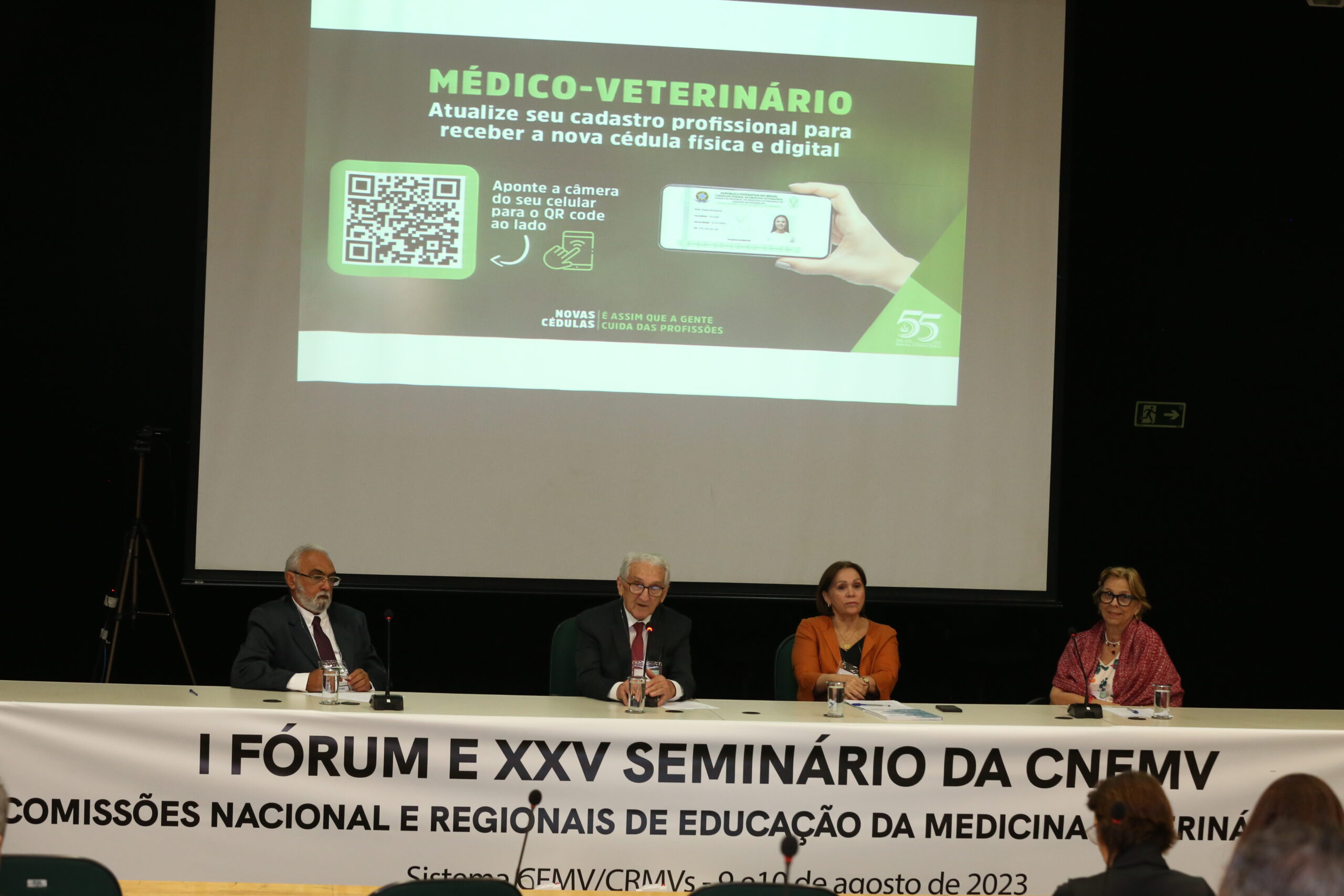 Na foto, está a mesa do evento com os membros principais, entre os quais o presidente do CFMV. Há uma faixa escrita Primeiro Fórum e Vigésimo Quinto Seminário das Comissões Nacional e Regionais de Educação da Medicina Veterinária.