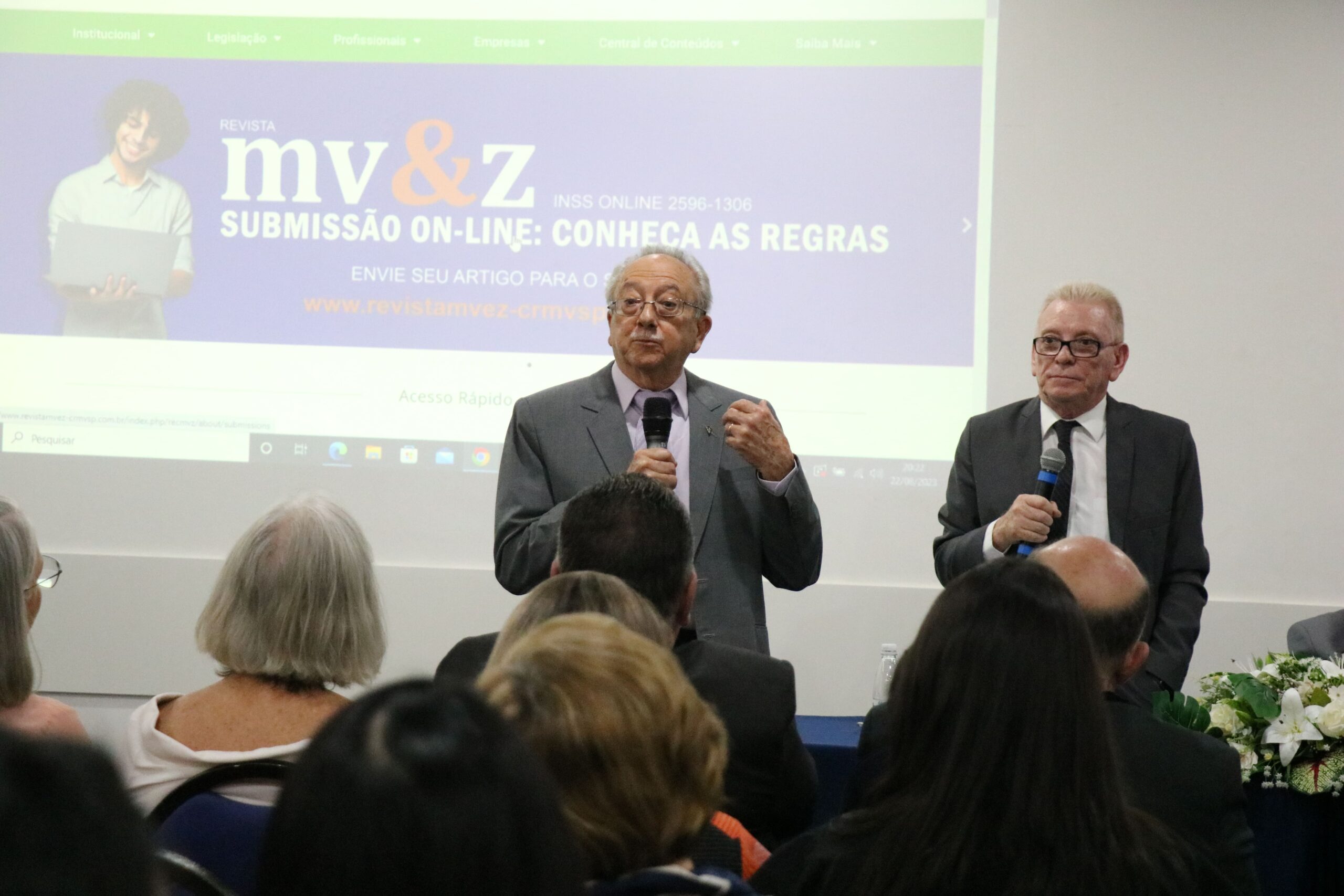 Na foto aparece em frente a um telão, o representante regional de Campinas e o presidente do CRMV-SP, ambos estão de pé e falam ao microfone.