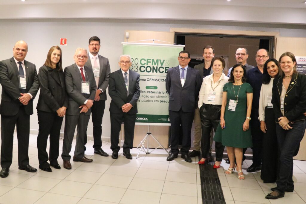 Imagem mostra integrantes da diretoria do CRMV-SP, representantes do CFMV, incluindo o presidente do órgão, bem como palestrantes do evento reunidos de pé com banner do evento ao centro da foto. São ao todo 13 pessoas, sendo cinco mulheres.