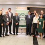 Imagem mostra integrantes da diretoria do CRMV-SP, representantes do CFMV, incluindo o presidente do órgão, bem como palestrantes do evento reunidos de pé com banner do evento ao centro da foto. São ao todo 13 pessoas, sendo cinco mulheres.