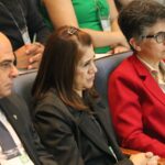 Imagem foca em três pessoas sentadas no auditório. Duas mulheres e um homem. Trata-se do vice-presidente e a tesoureira do CRMV-SP, e a presidente da Comissão Técnica de Pesquisa Clínica. Eles estão atentos a palestra e aparecem de perfil.