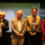 Na imagem estão dois homens e duas mulheres. Ao microfone está o presidente do CMFV.