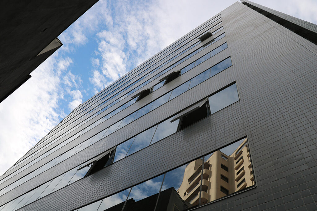 A imagem mostra a vista lateral nova do prédio, com janelas espelhadas e superfície em pastilha de cor verde.