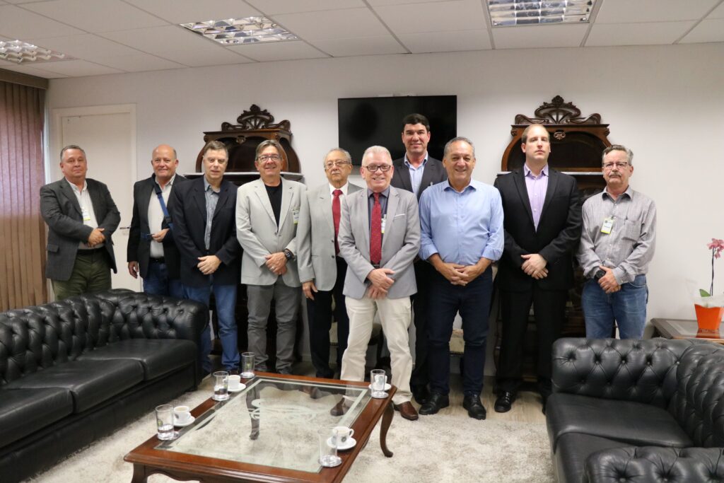 Na foto estão onze homens posando de pé para a câmera. Eles sorriem para a foto e estão em uma ampla sala do gabinete da Câmara Municipal de Campinas.