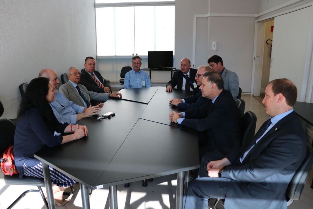 Na foto aparece a comitiva do CRMV-SP reunida com o vereador e a sua suplente. São nove homens e uma mulher sentados ao entorno de uma mesa preta.