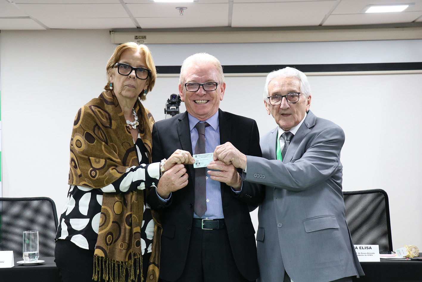 A foto mostra o presidente do CFMV, Francisco Cavalcanti de Almeida, a vice-presidente do Federal, Ana Elisa Almeida, e o presidente do CRMV-SP, Odemilson Donizete Mossero, segurando a cédula de identidade profissional.