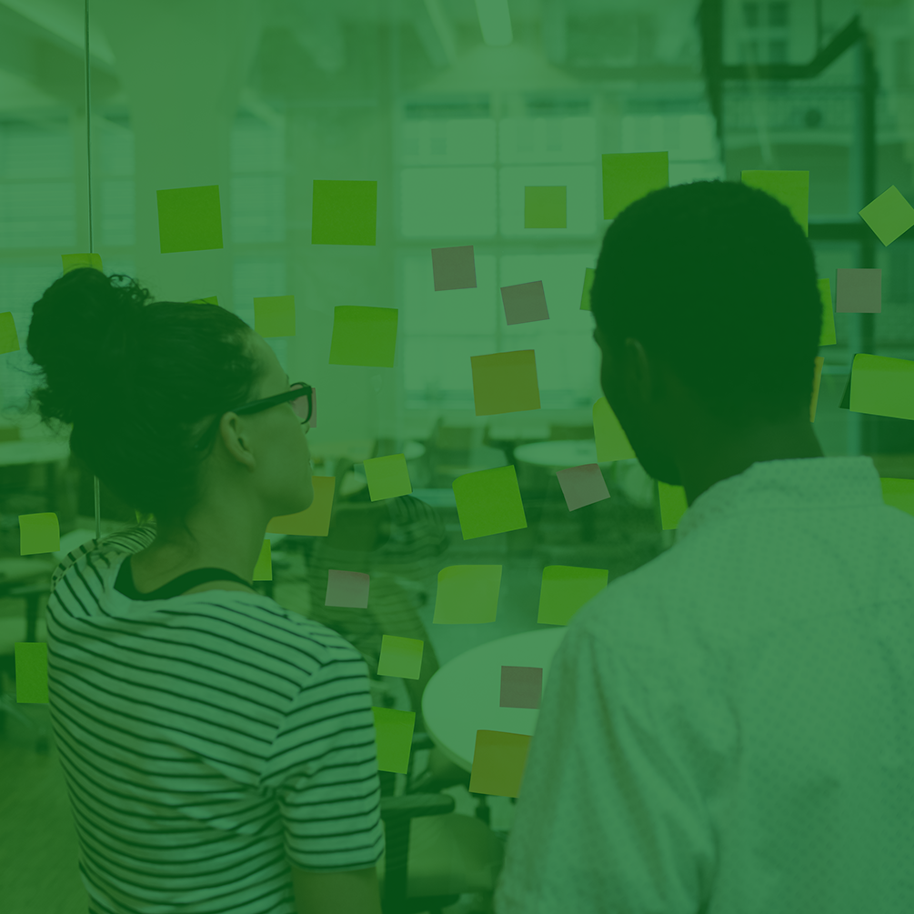 um homem e uma mulher de costas olhando para um mural de avisos