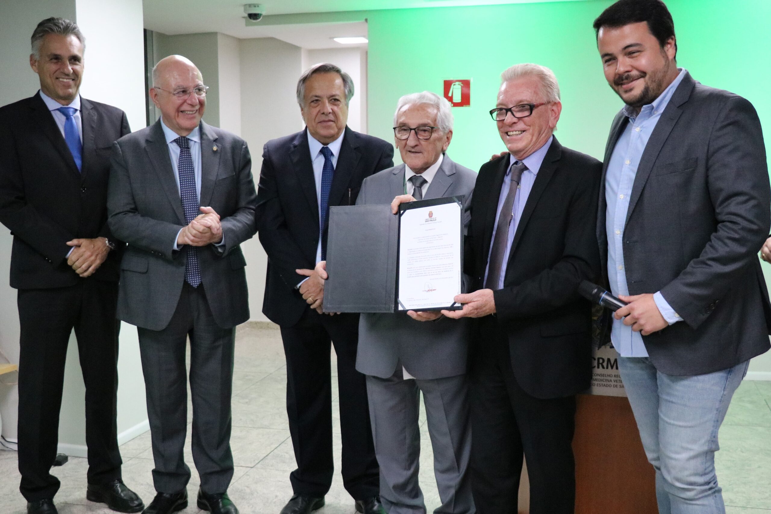 Estão na foto o presidente do CFMV e ex-presidente do CRMV-SP, Francisco Cavalcanti de Almeida; o ex-presidente, Mário Eduardo Pulga; o presidente do Regional na atual gestão, Odemilson Donizete Mossero; o deputado federal, Arnaldo Jardim; o superintendente federal de Agricultura e Pecuária de São Paulo, Guilherme Campos; o médico-veterinário e vereador da cidade de São Paulo, Rodrigo Goulart. O presidente do CRMV-SP recebe a placa de homenagem da Câmara Municipal – voto de júbilo.