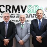 O presidente atual e os presidentes anteriores do CRMV-SP, Odemilson Donizete Mossero, Francisco Cavalcanti de Almeida e Mário Eduardo Pulga, posam em frente ao logotipo do Regional, que são letras na parede com o nome do Conselho e os símbolos da Medicina Veterinária e da Zootecnia.