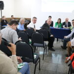 A imagem traz um homem com o microfone na mão fazendo uma pergunta e sendo observado pelos representantes do CRMV-SP que estão à mesa e pelos demais participantes do evento.