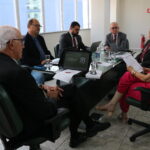 Na foto, estão sentados e conversam os participantes da reunião do PRODES: o presidente do CRMV-SP, Odemilson Donizete Mossero (primeiro ao fundo); o conselheiro do CFMV, Paulo Araújo de Guerra (à direita); a vice-presidente do CFMV, Ana Elisa de Souza Almeida; o conselheiro do CFMV, Marcílio Magalhães Vaz de Oliveira (primeiro, à frente); o presidente do CRMV-BA, Altair Santana de Oliveira (primeiro, à direita); o assessor administrativo, chefe do Núcleo de Apoio aos Regionais (NAR) do CFMV, Igor Pinto de Andrade; e a presidente do CRMV-PE, Maria Elisa Araújo.