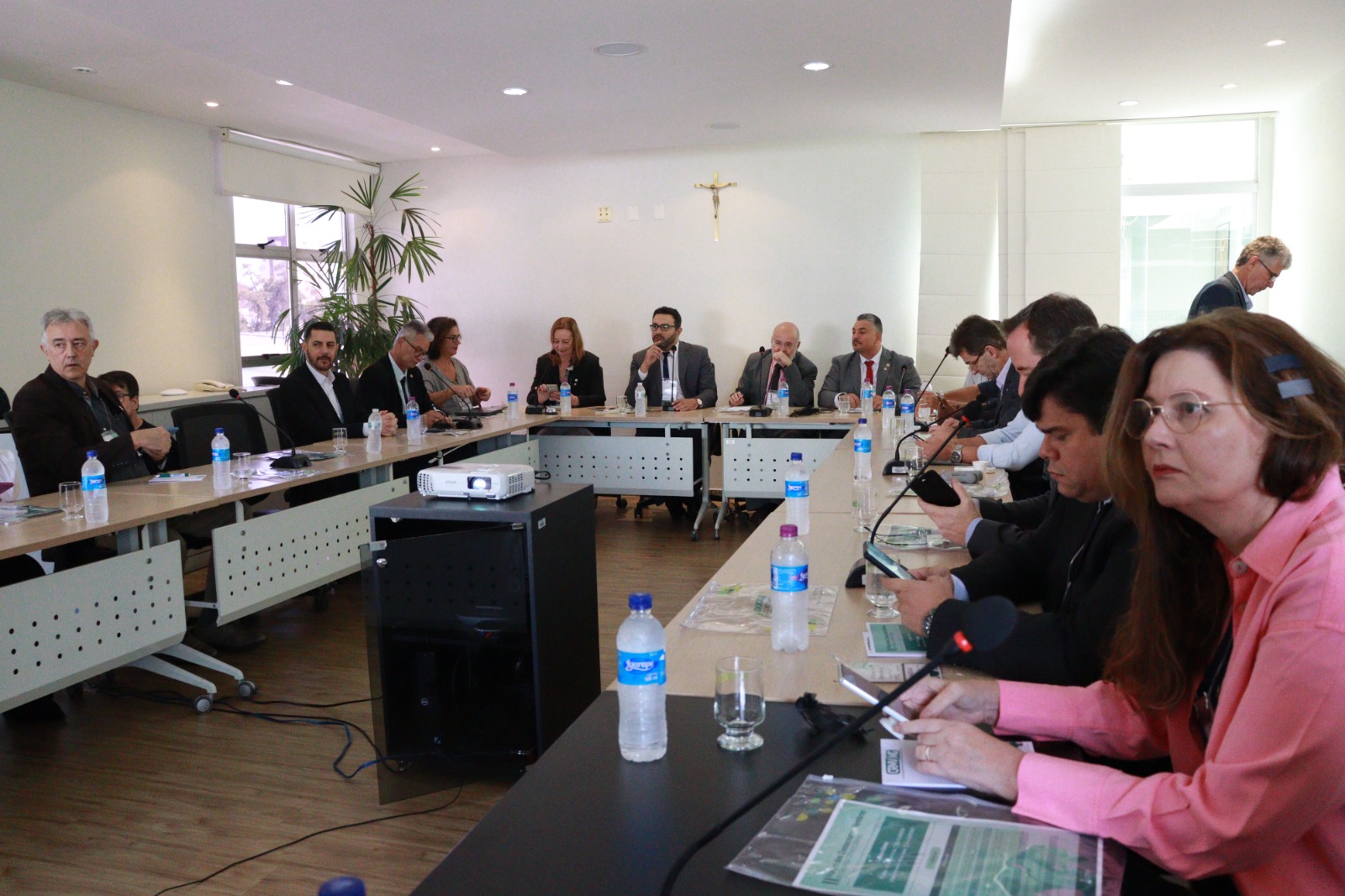 A foto mostra os participantes, sentados durante o evento.