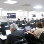 Na foto, membros do plenário estão sentados na sala.