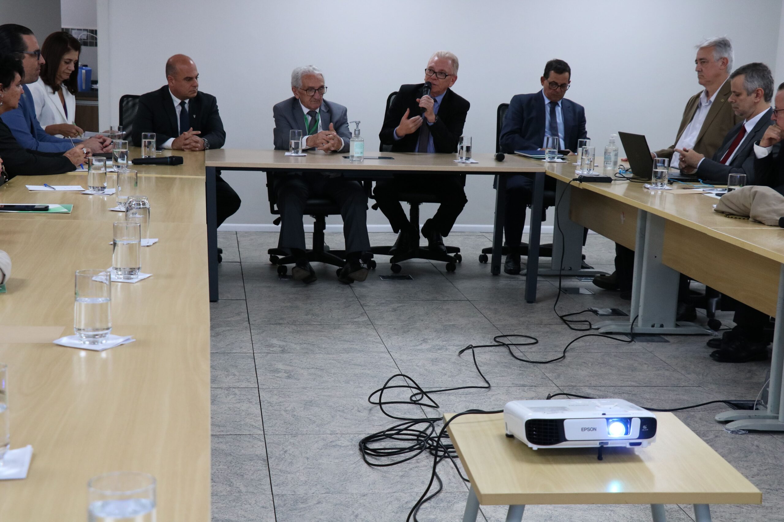 Visão parcial da sala mostra oito presidentes de comissões, o presidente do CFMV, e o presidente do CRMV-SP. Todos estão sentados e atentos a fala do presidente do CRMV-SP, que segura um microfone.