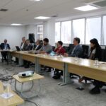 Visão lateral da sala. Em que é possível ver os presentes em dois dos lados do "U" formado pela disposição das mesas. No canto esquerdo da imagem, o presidente do CRMV-SP fala do microfone.