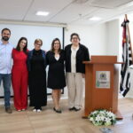 Cinco pessoas, sendo um homem e quatro mulheres, em pé, lado a lado, posando para a foto.