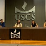 Na foto, membros da Comissão estão sentados no palco do evento.