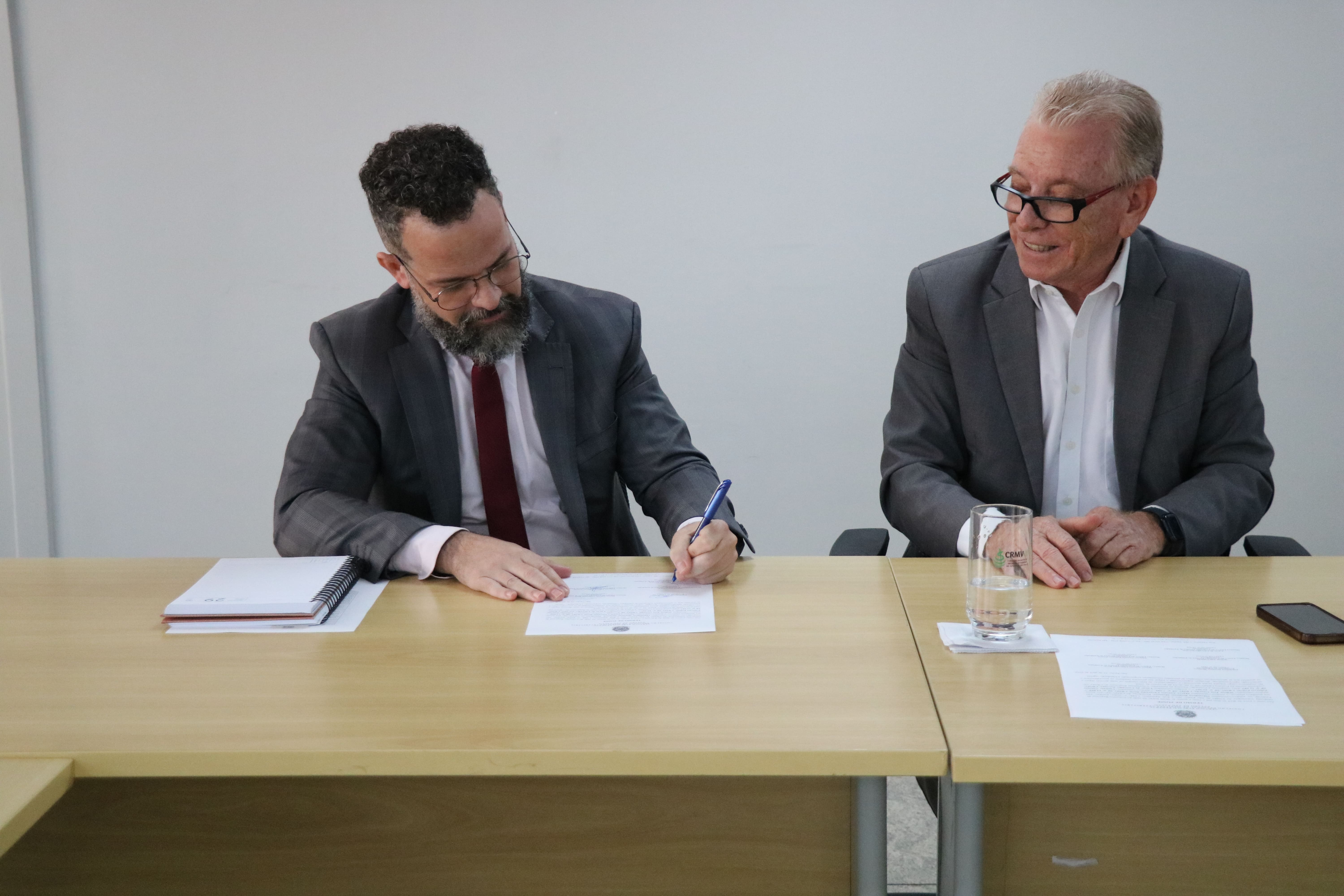 Na foto, o médico-veterinário Lucas de Carvalho Navajas assina a posse como membro da Comissão de Entidades Veterinárias Regionais do Estado de São Paulo do CRMV-SP, ao lado do presidente do CRMV-SP, Odemilson Donizete Mossero.