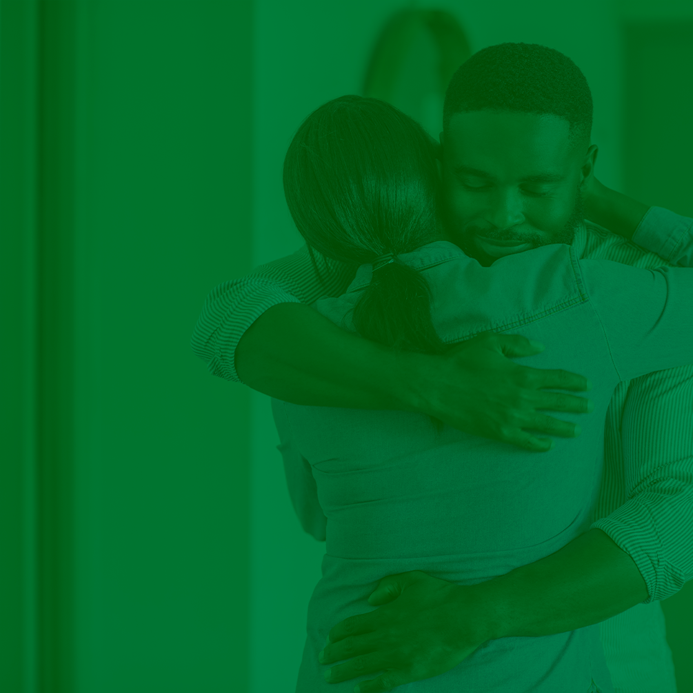 Imagem ilustrativa traz duas pessoas se abraçando. A imagem tem filtro verde aplicado.