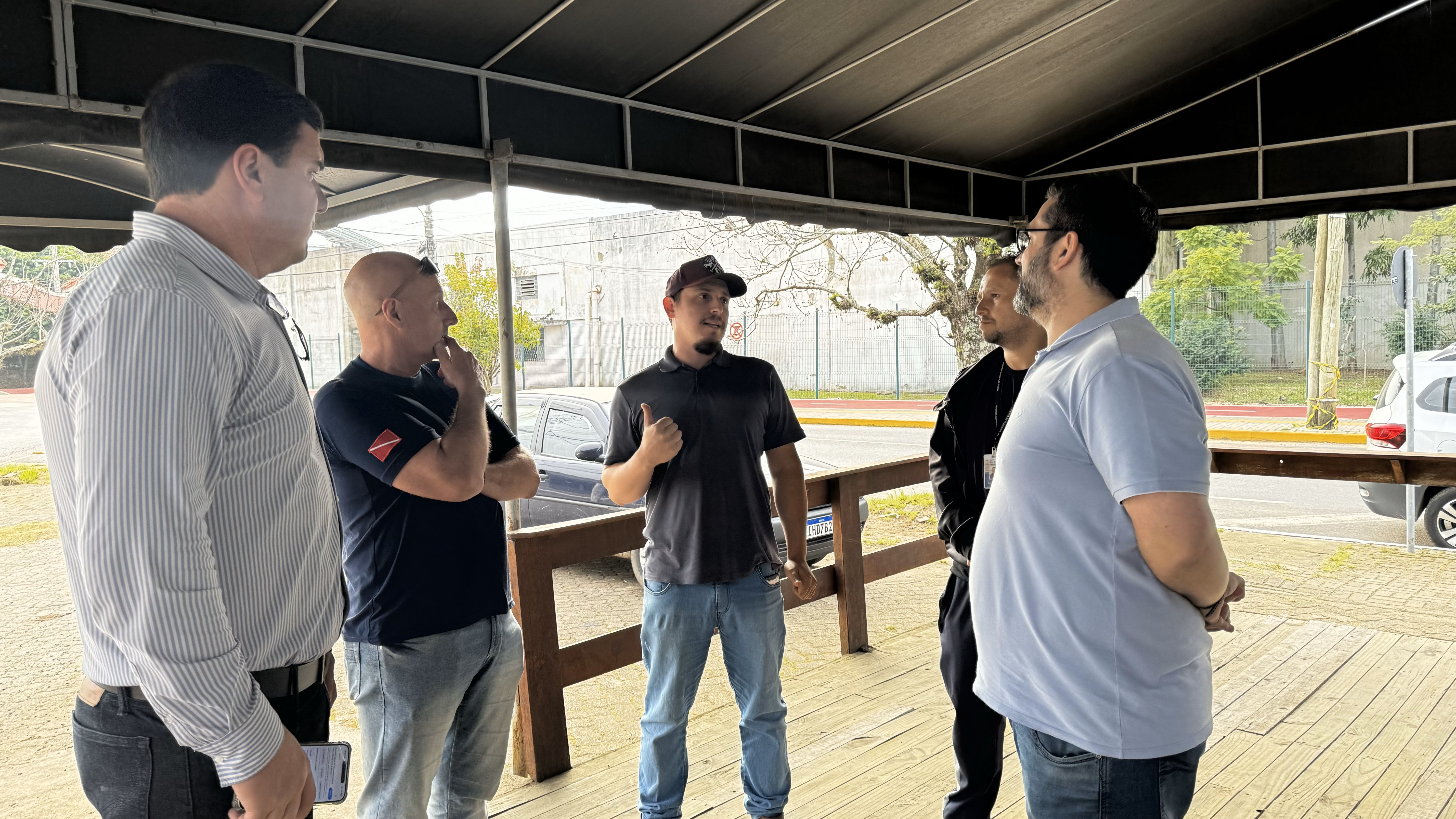 Cinco homens em pé, conversando durante grupo de trabalho que mapeia a saúde dos animais no Rio Grande do Sul.