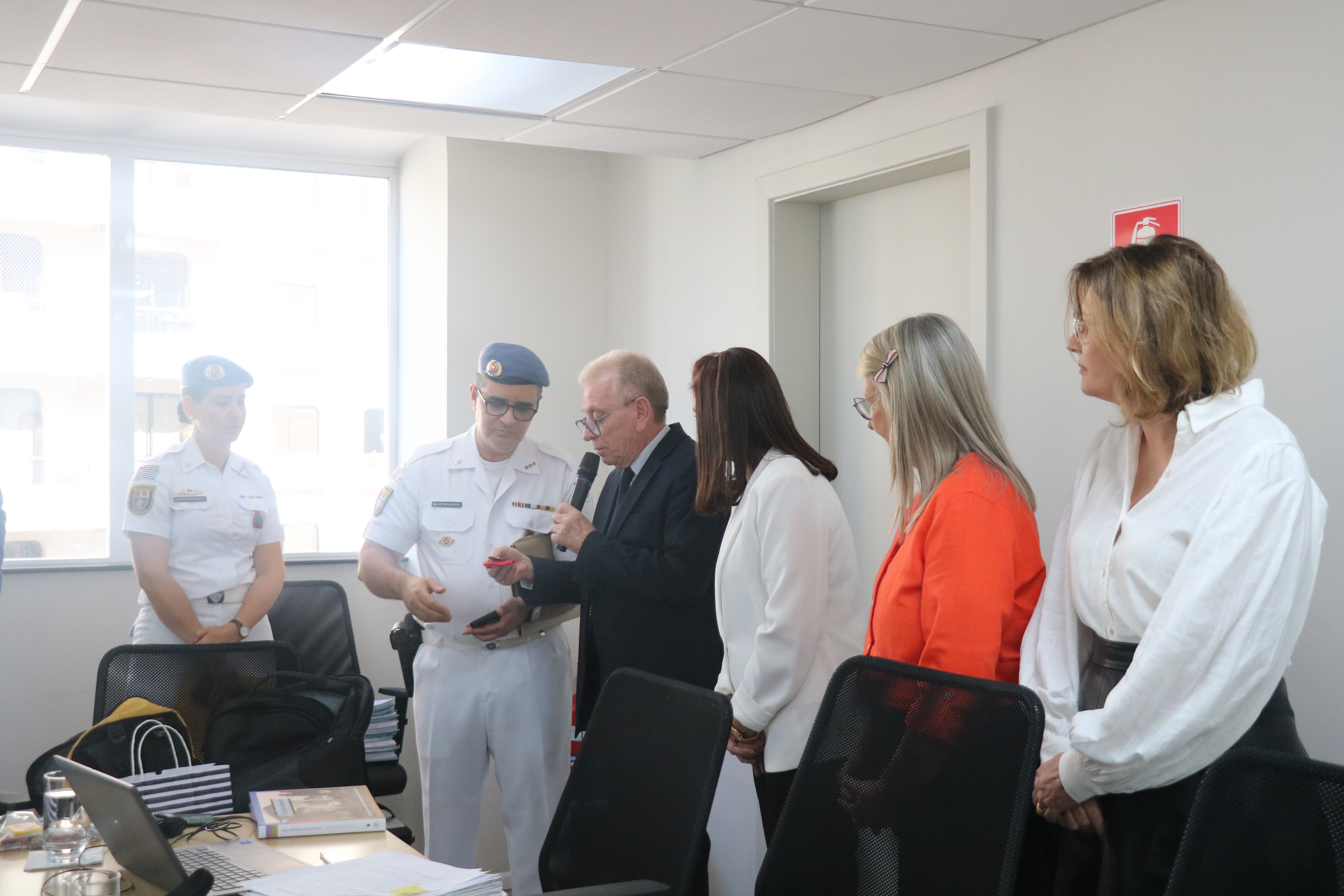 Visão lateral direita dos médicos-veterinários(uma mulher e um homem) militares recebendo medalha de homenagem do presidente do CRMV-SP.