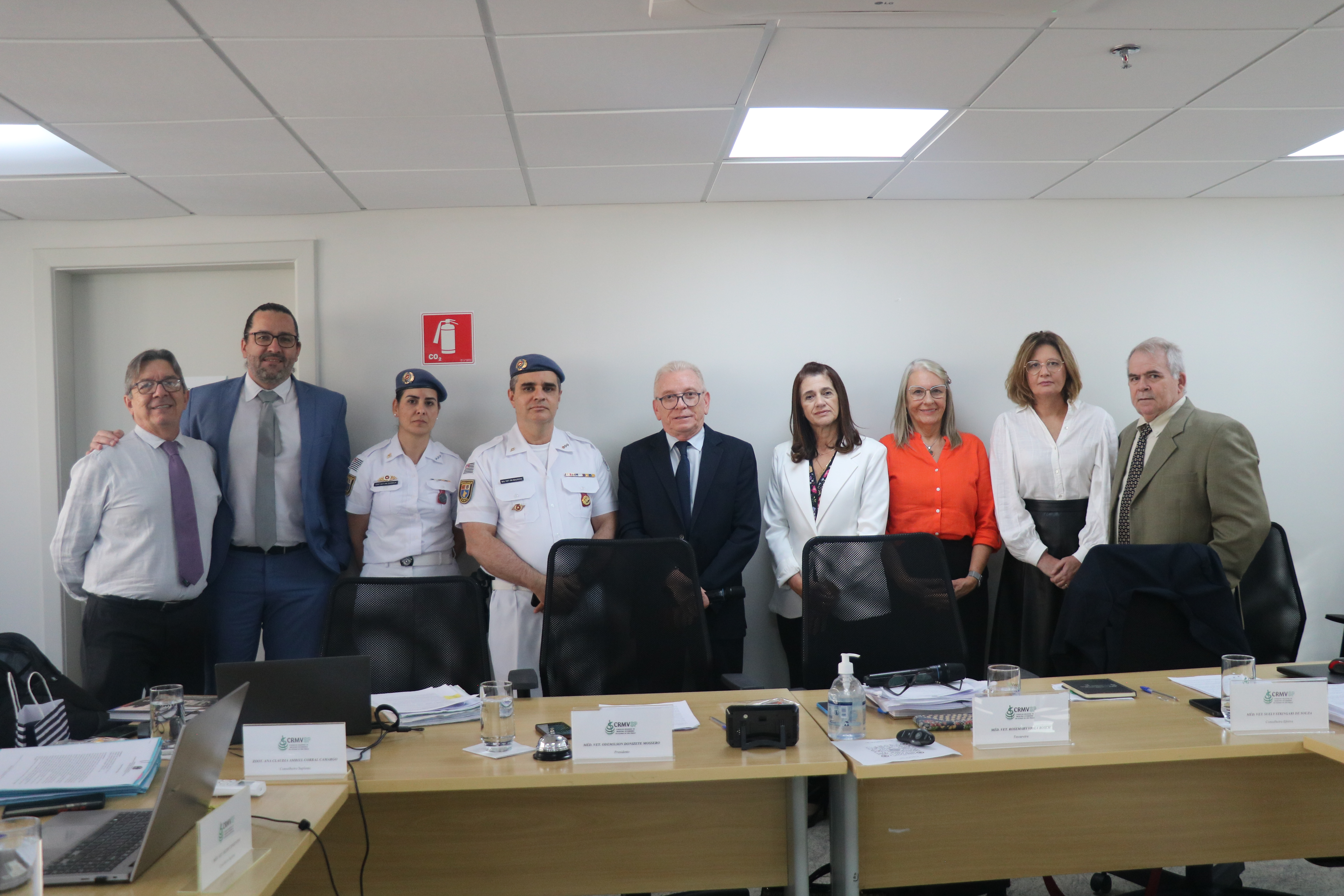 Cinco mulheres e quatros homens em pé, pousando para foto na sala da plenária do CRMV-SP, no centro, o presidente do CRMV_SP, Odenilson.