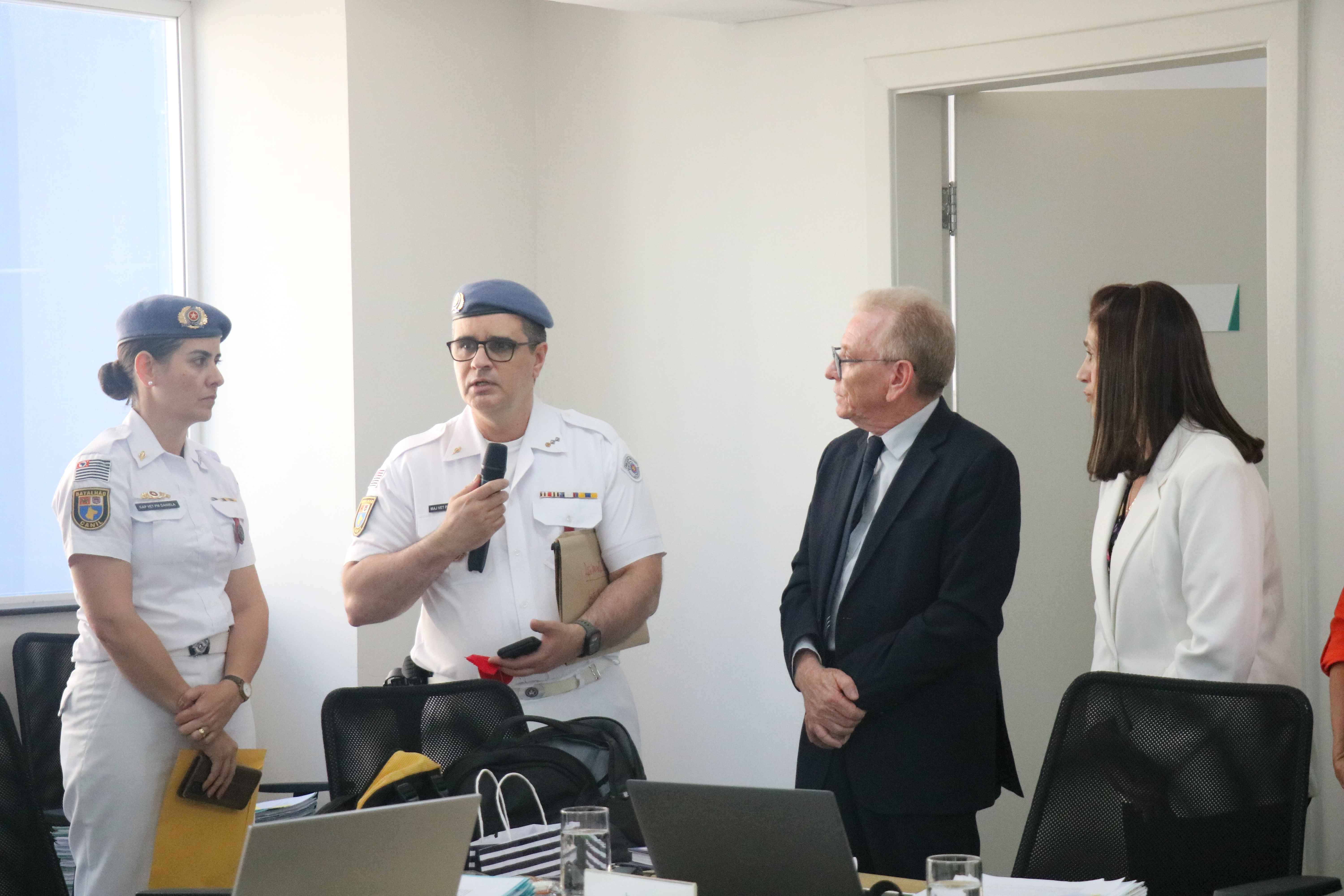 Visão lateral direita dos médicos-veterinários(uma mulher e um homem) militares recebendo medalha de homenagem do presidente do CRMV-SP.
