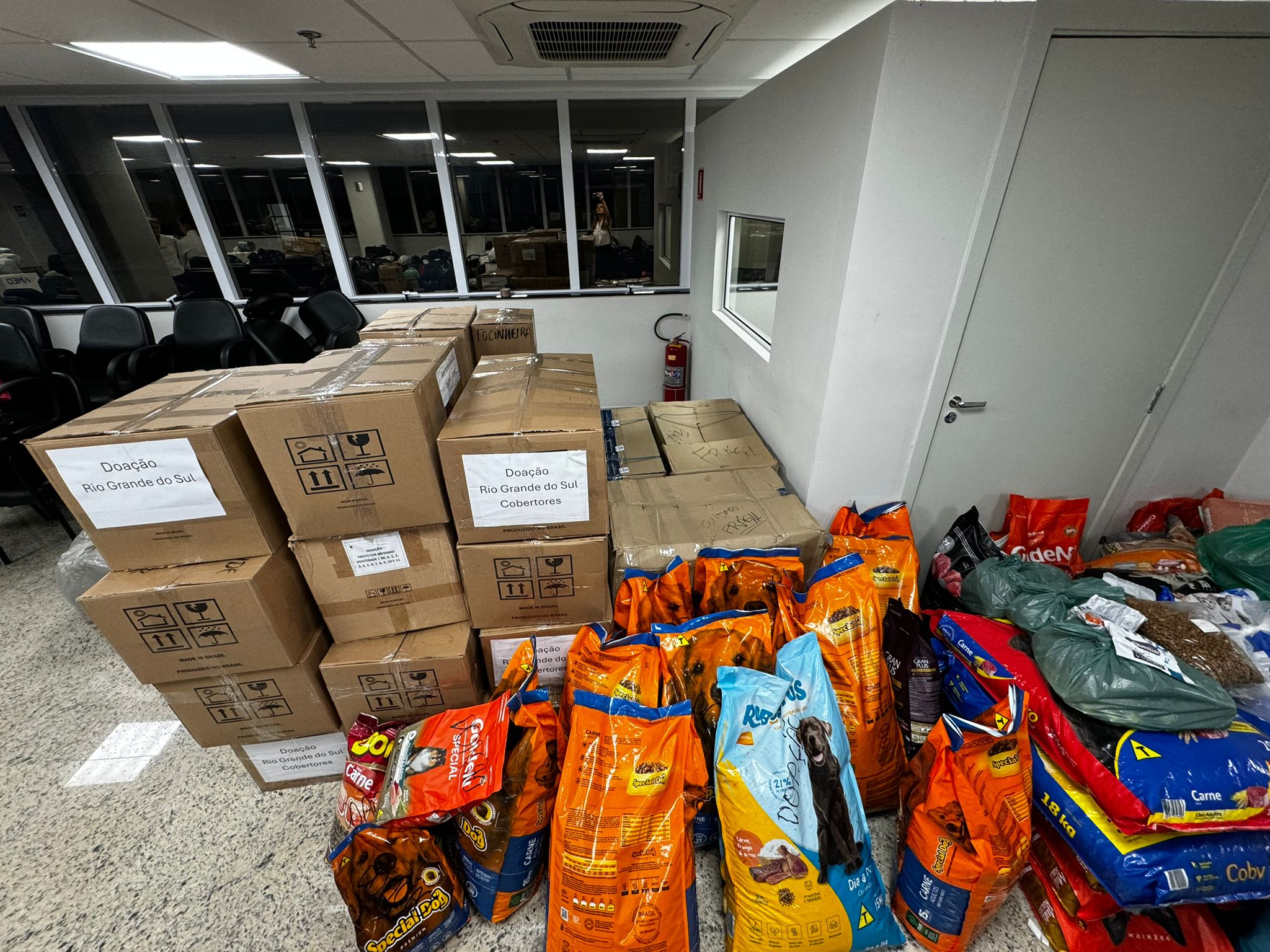 Chão com pacotes grandes de ração canina para vítimas das enchentes no Rio Grande do Sul.