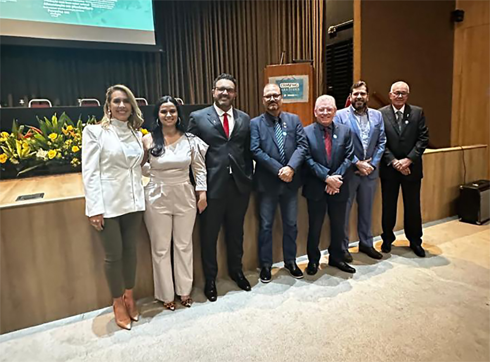 Pessoas fotografadas em pé, em um auditório em Minas Gerais.