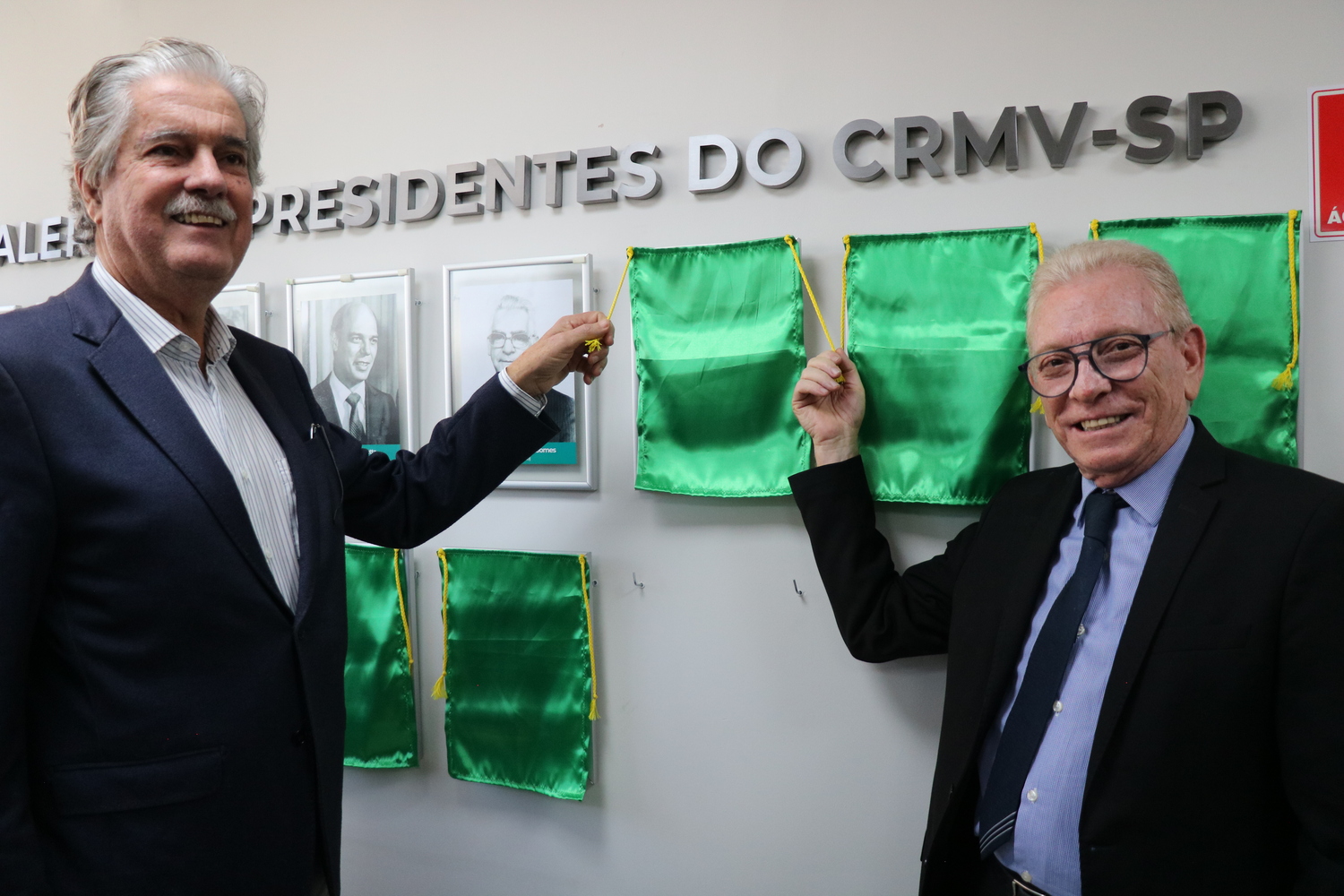 O presidente do CRMV-SP descerra foto na Galeria de Presidentes, ao lado de ex-presidente homenageado.