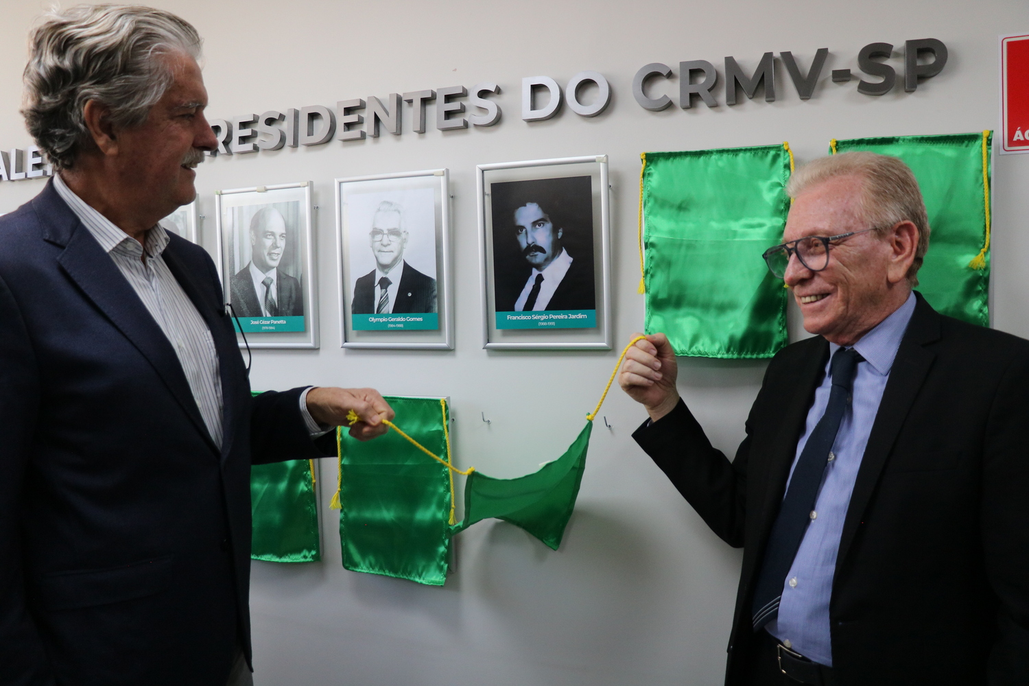 O presidente do CRMV-SP descerra foto na Galeria de Presidentes, ao lado de ex-presidente homenageado.