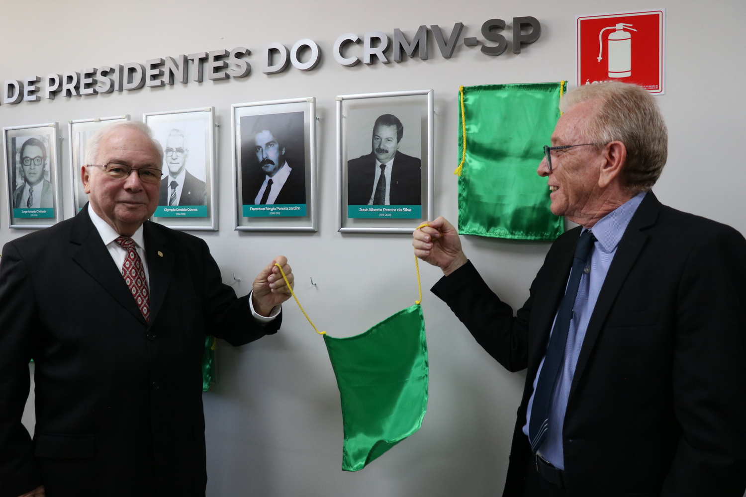 O presidente do CRMV-SP descerra foto na Galeria de Presidentes, ao lado de ex-presidente homenageado.