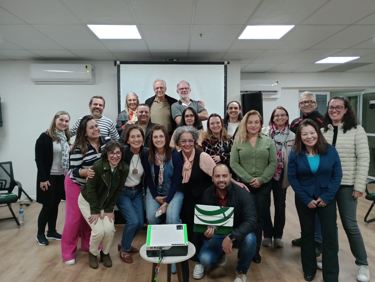 Pessoas pousando para foto em sala de treinamento.