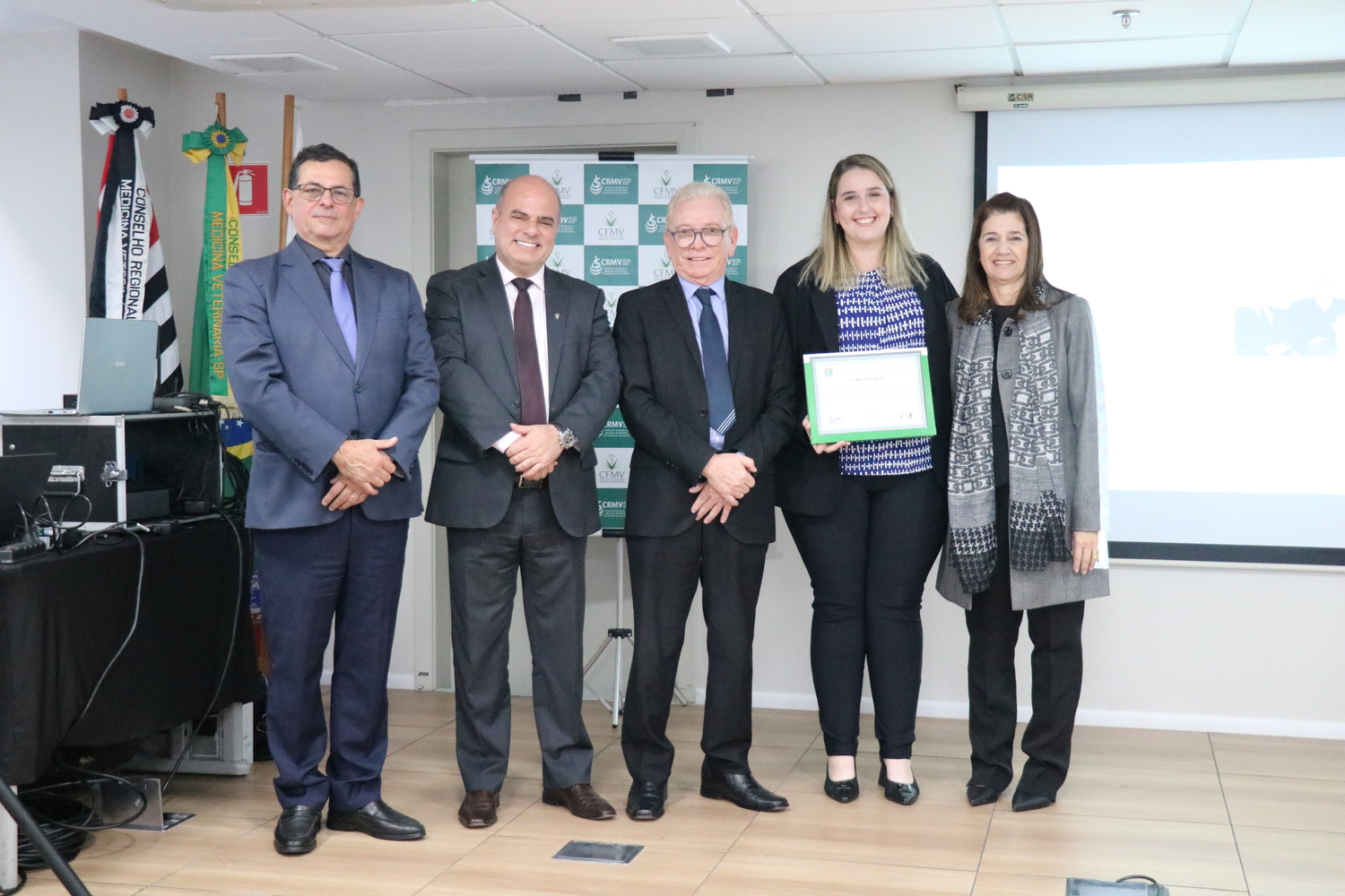 No palco, os membros da Diretoria Executiva do CRMV-SP posam ao lado de uma das integrantes da Comissão Técnica de Representantes Regionais, homenageado com certificado em reconhecimento ao trabalho desempenhado.