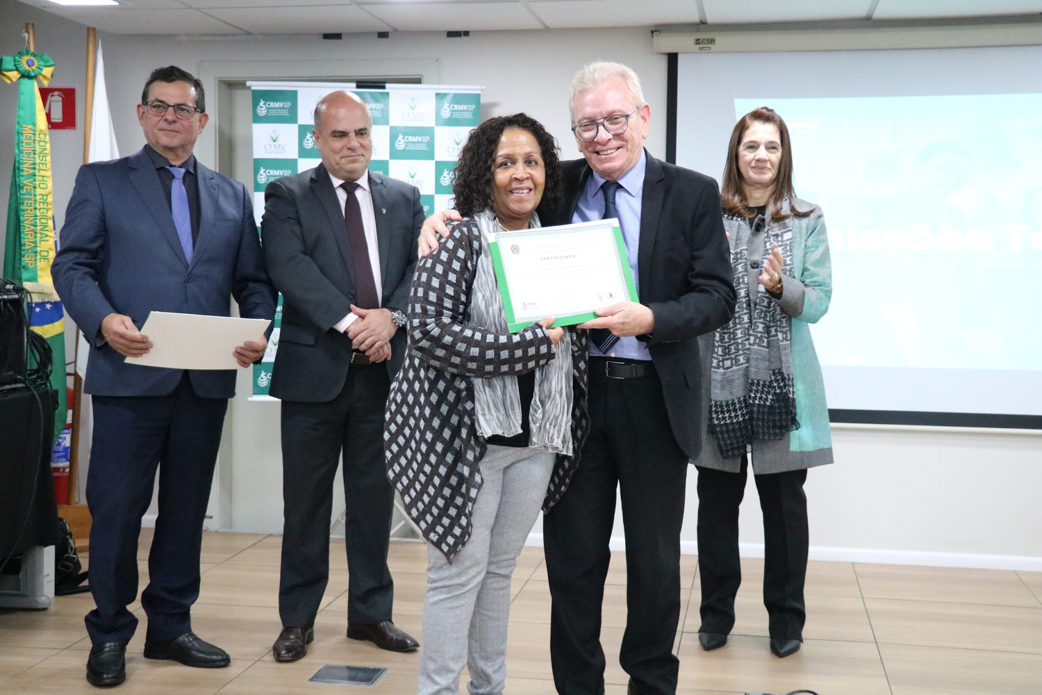 No palco, ao lado dos membros da Diretoria Executiva, o presidente do CRMV-SP entrega certificado para a presidente de Comissão Técnica.
