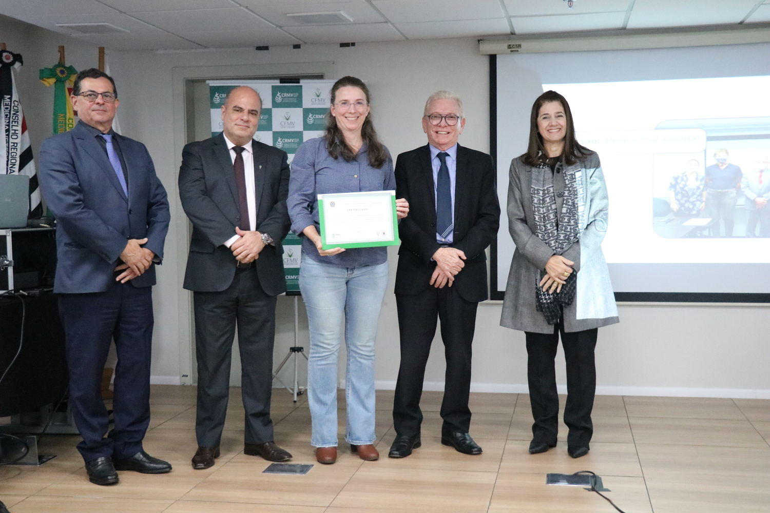No palco, os membros da Diretoria Executiva do CRMV-SP posam ao lado de uma presidente de Comissão Técnica homenageada com certificado em reconhecimento ao trabalho desempenhado.