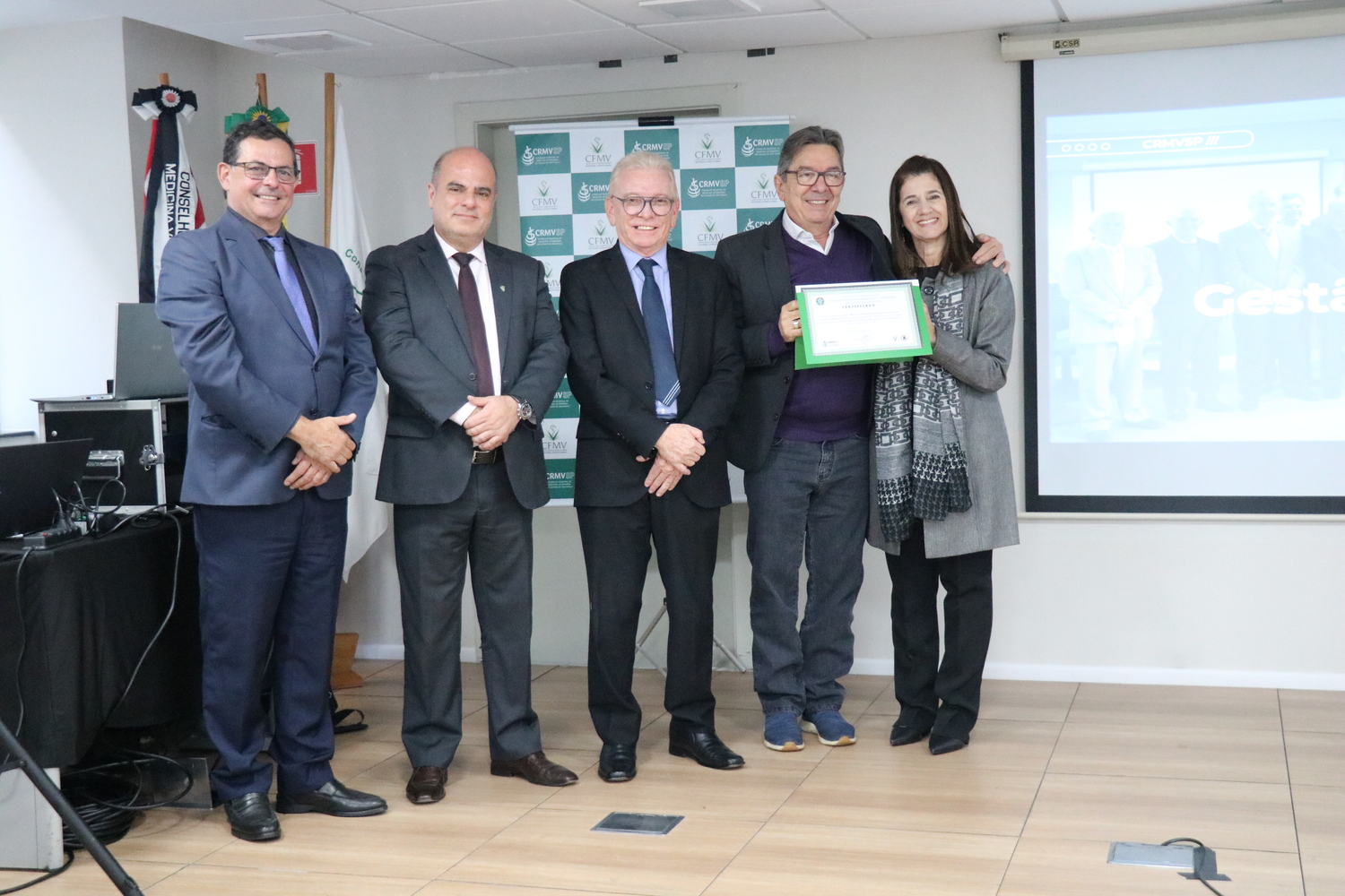 No palco, os membros da Diretoria Executiva do CRMV-SP posam ao lado de conselheiro da autarquia homenageado pelo trabalho desempenhado em suas funções.