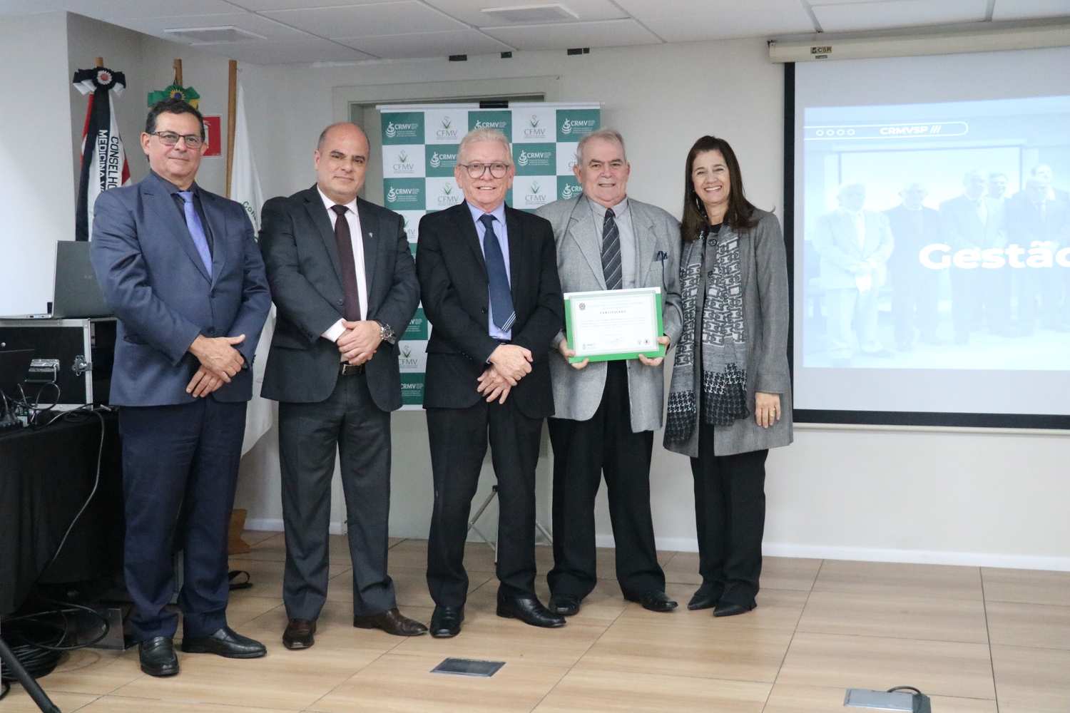 No palco, os membros da Diretoria Executiva do CRMV-SP posam ao lado de conselheiro da autarquia homenageado pelo trabalho desempenhado em suas funções.