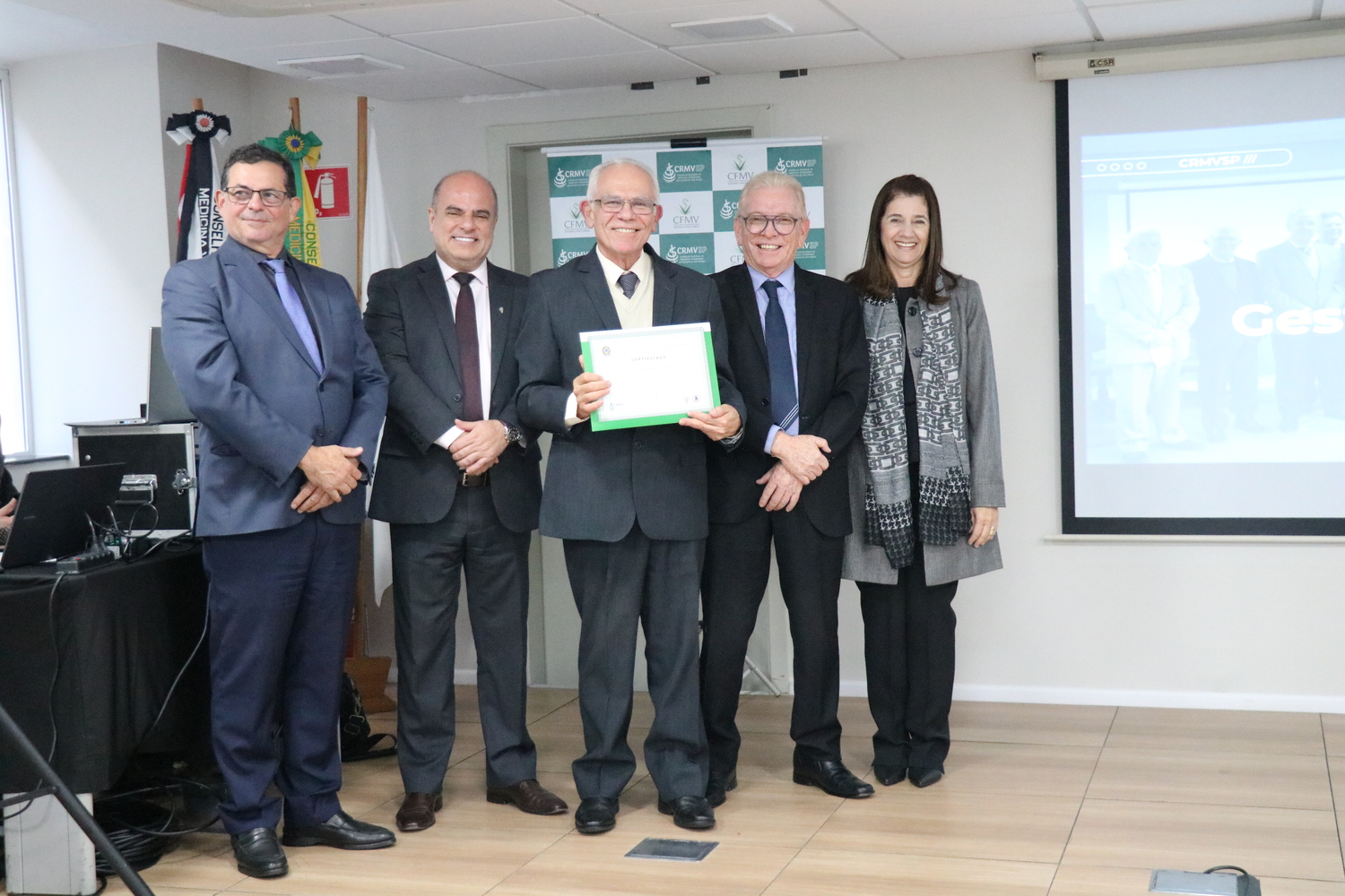 No palco, os membros da Diretoria Executiva do CRMV-SP posam ao lado de conselheiro da autarquia homenageado pelo trabalho desempenhado em suas funções.