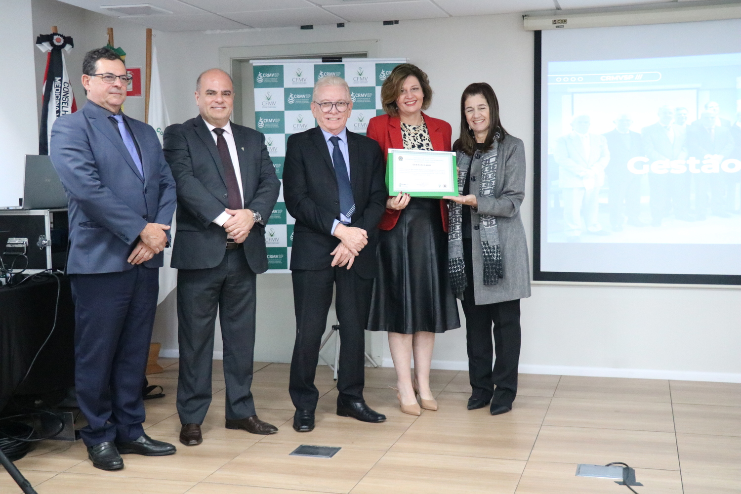 No palco, os membros da Diretoria Executiva do CRMV-SP posam ao lado de conselheira da autarquia homenageada pelo trabalho desempenhado em suas funções.